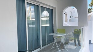 A balcony with a glass door, a small table, and a chair.