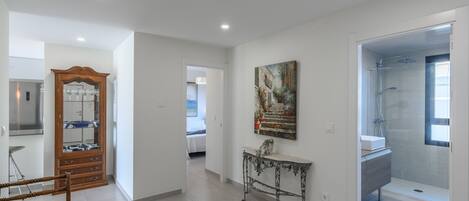 A spacious hallway with a wooden cabinet, a console table, and a painting on the wall.
