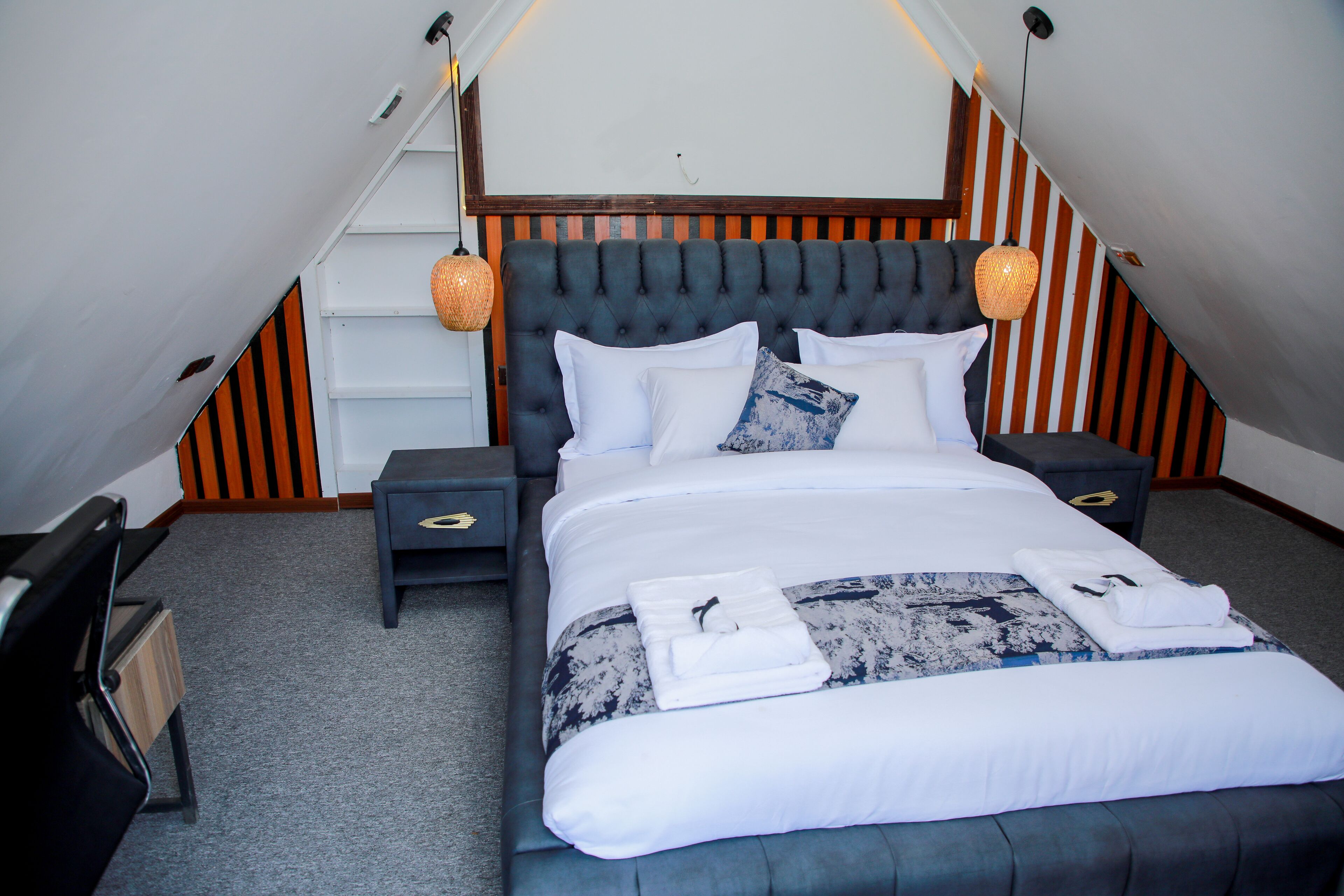 Una camera da letto ordinata con un letto grande, due comodini e una testiera a righe.
