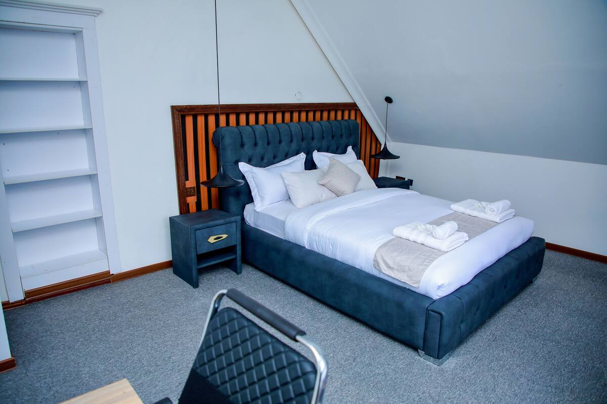 A neatly arranged bedroom with a bed, bedside tables, a chair, and a wardrobe.