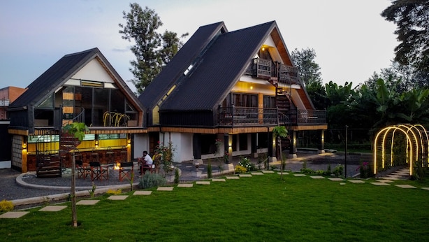 Ein modernes Gebäude mit einer großen Glasfassade, einer Holzdielen-Terrasse und einem gepflegten Garten.