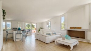 Un amplio espacio de sala con un sofá blanco, una mesa de comedor y una chimenea.