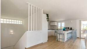 Una cocina moderna con una isla central, taburetes de bar y vistas al exterior.