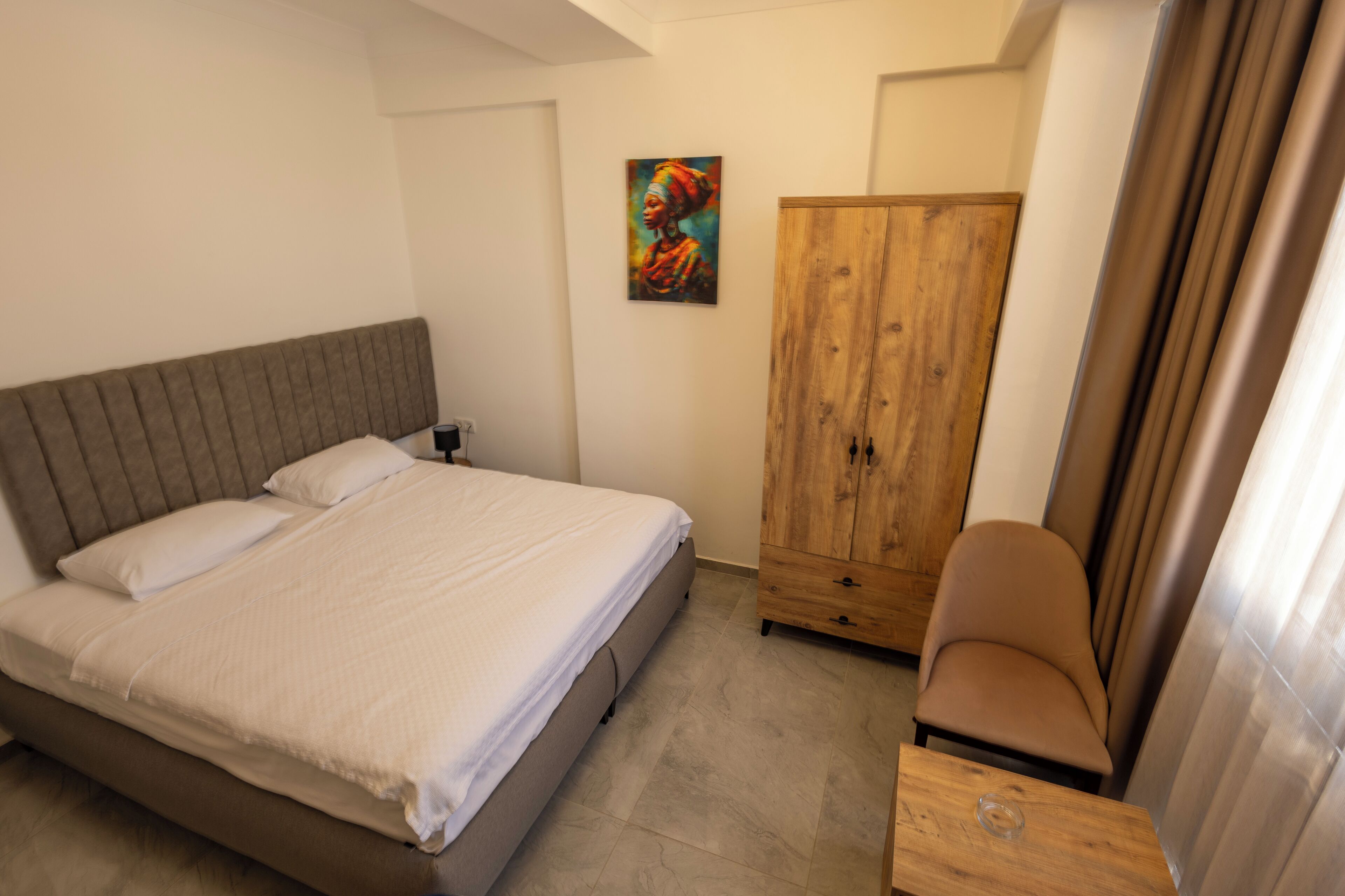 Un dormitorio con una cama, un armario de madera y una silla.