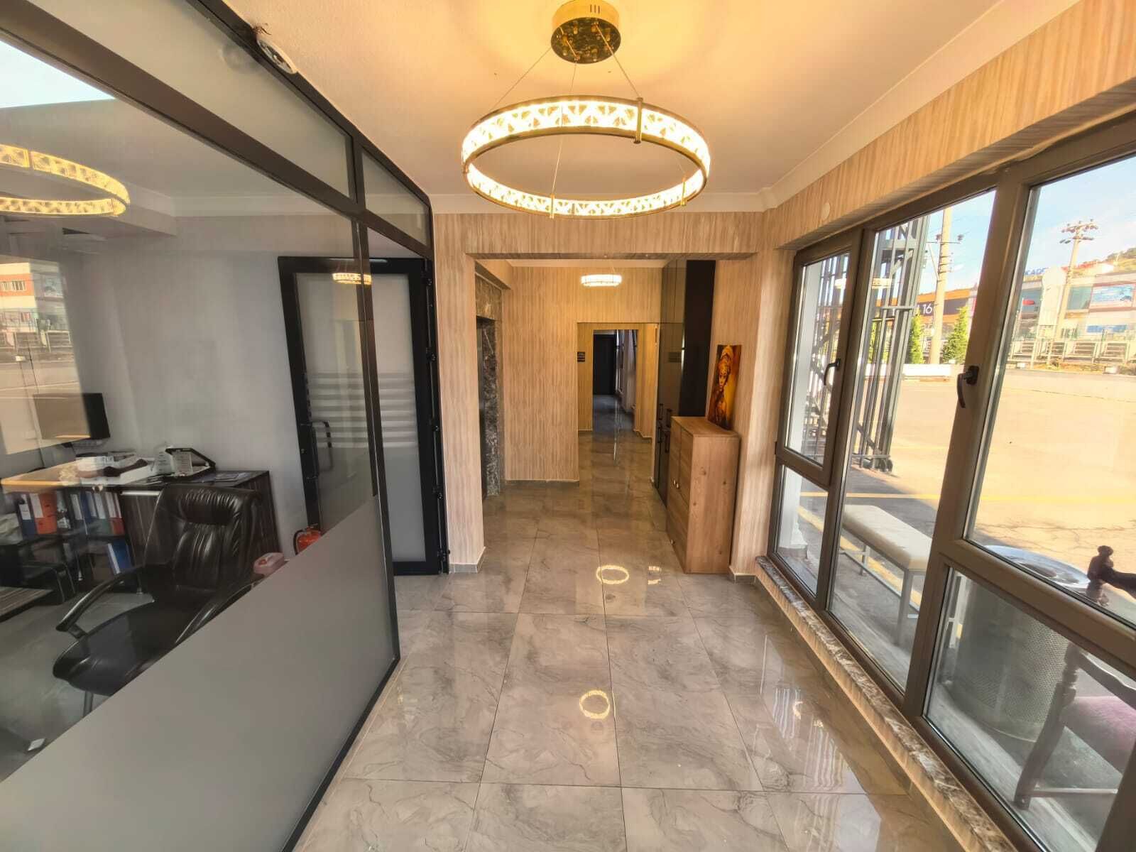 Vestíbulo de hotel con diseño moderno, que incluye un mostrador de recepción, una lámpara de araña grande y vistas a través de puertas de cristal.