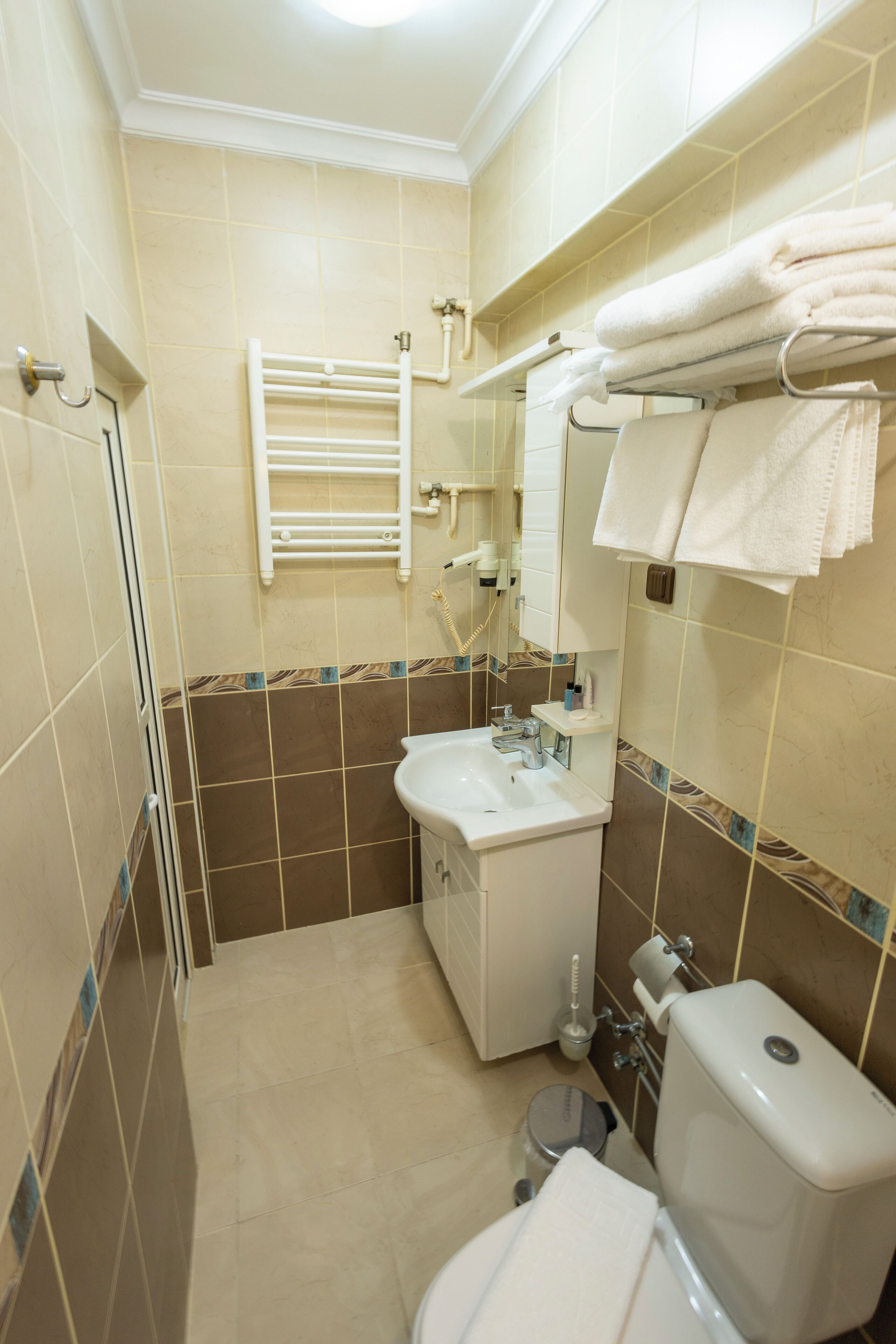 Une salle de bain équipée d’un lavabo, de toilettes, d’un porte-serviettes et d’un miroir.