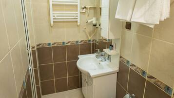 Une salle de bain équipée d’un lavabo, de toilettes, d’un porte-serviettes et d’un miroir.