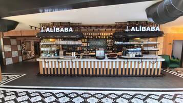 Zona de bar con dos letreros de Alibaba, una barra con varios artículos y un suelo con diseño.