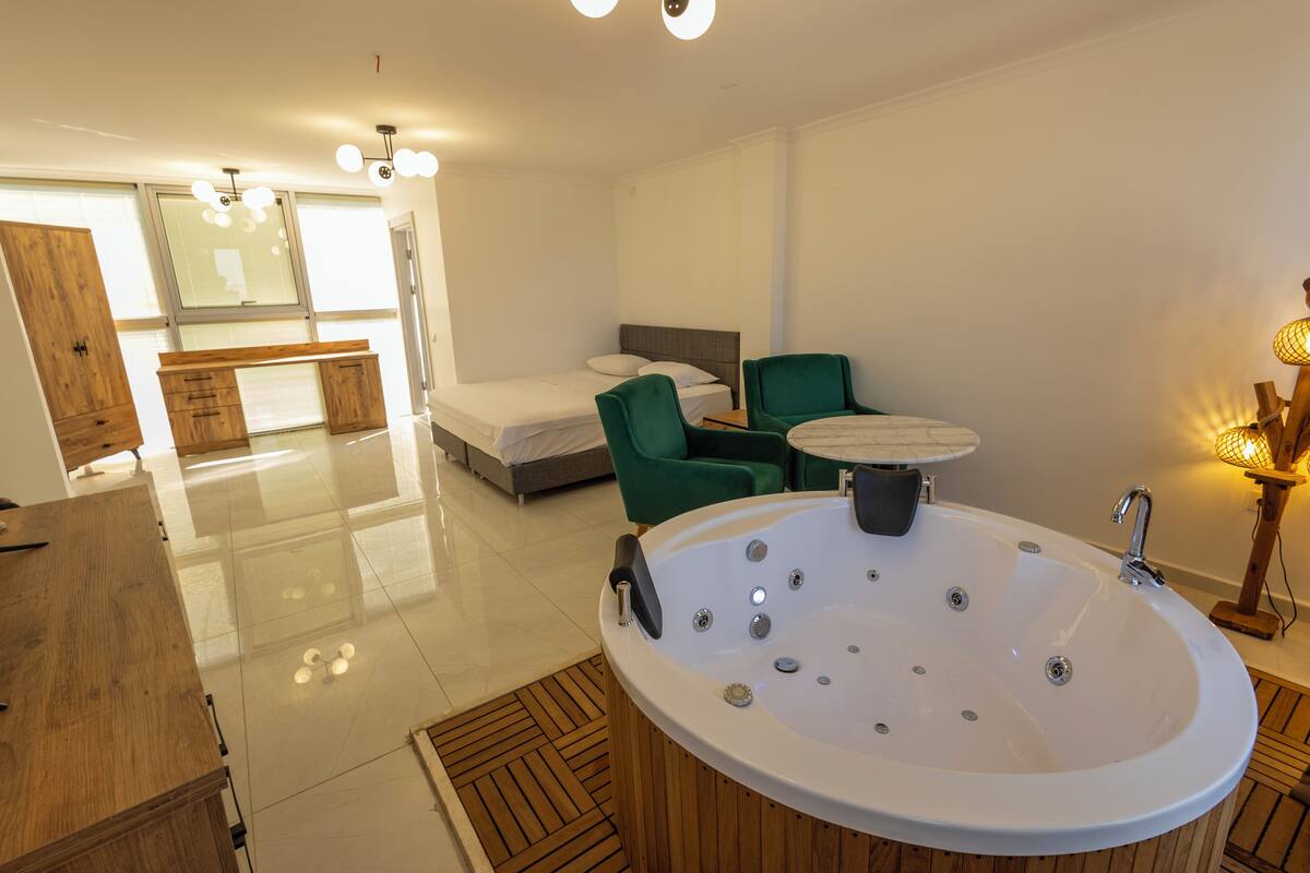A modern bathroom with a freestanding bathtub, a wooden vanity, and a green chair.
