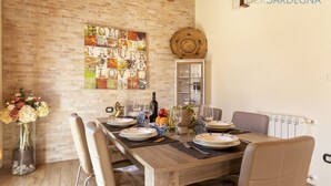 A dining area with a brick wall, a decorative sign, and a table set for four with chairs. - Alida penthouse in Alghero city centre, 4 bedrooms and 2 bathrooms for 8 people (Alghero)