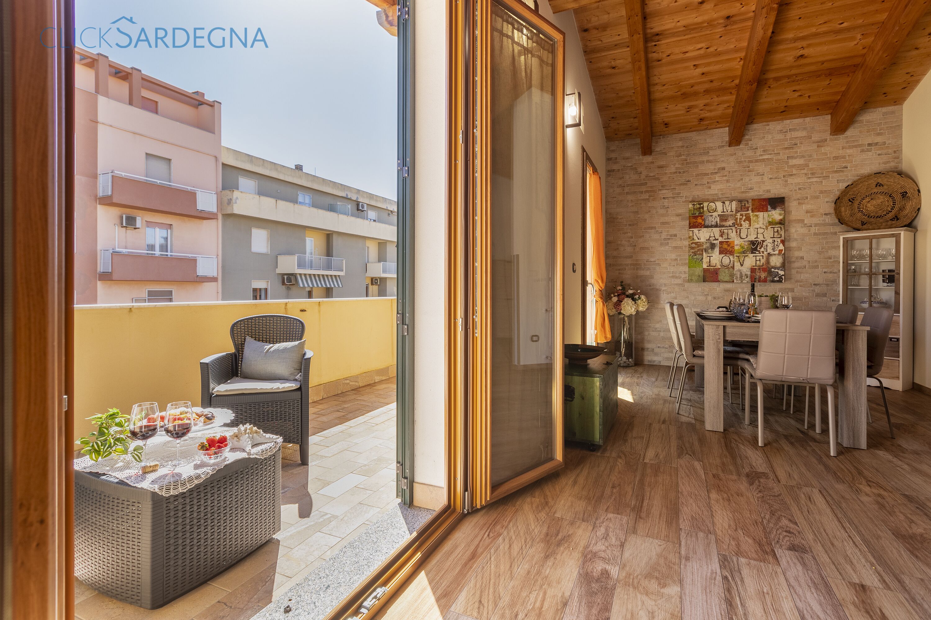 A balcony with wicker furniture, a dining table, and a view of neighboring buildings.