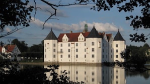 Un edificio parecido a un castillo con múltiples torres, rodeado de agua y árboles.