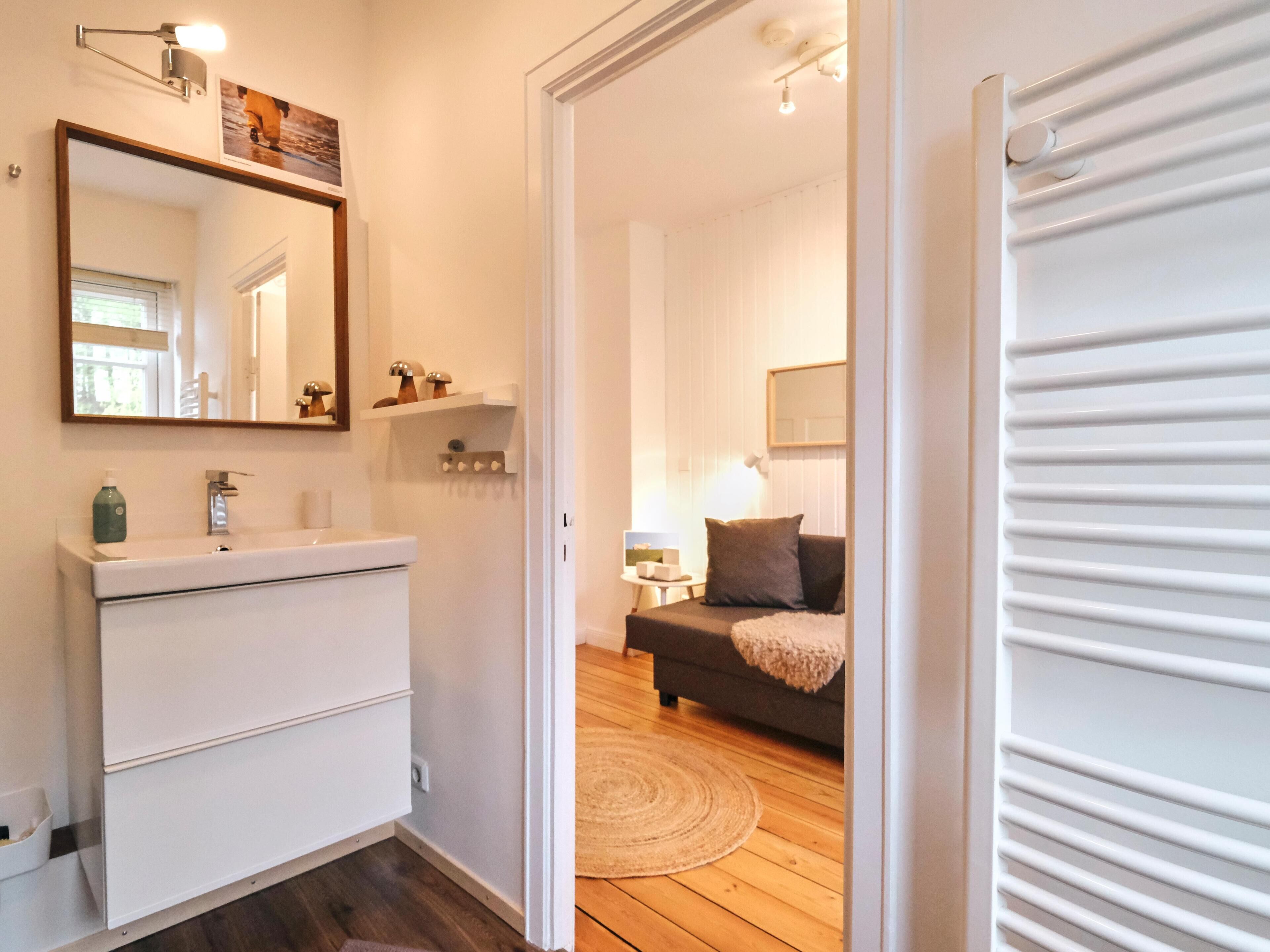 Een moderne badkamer met een wit wastafelmeubel, een spiegel en een plank met decoratieve voorwerpen.