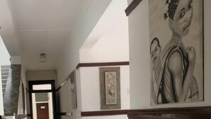 Ein Flur mit Fliesenboden, einer Tür am Ende und einem gerahmten Kunstwerk an der Wand.