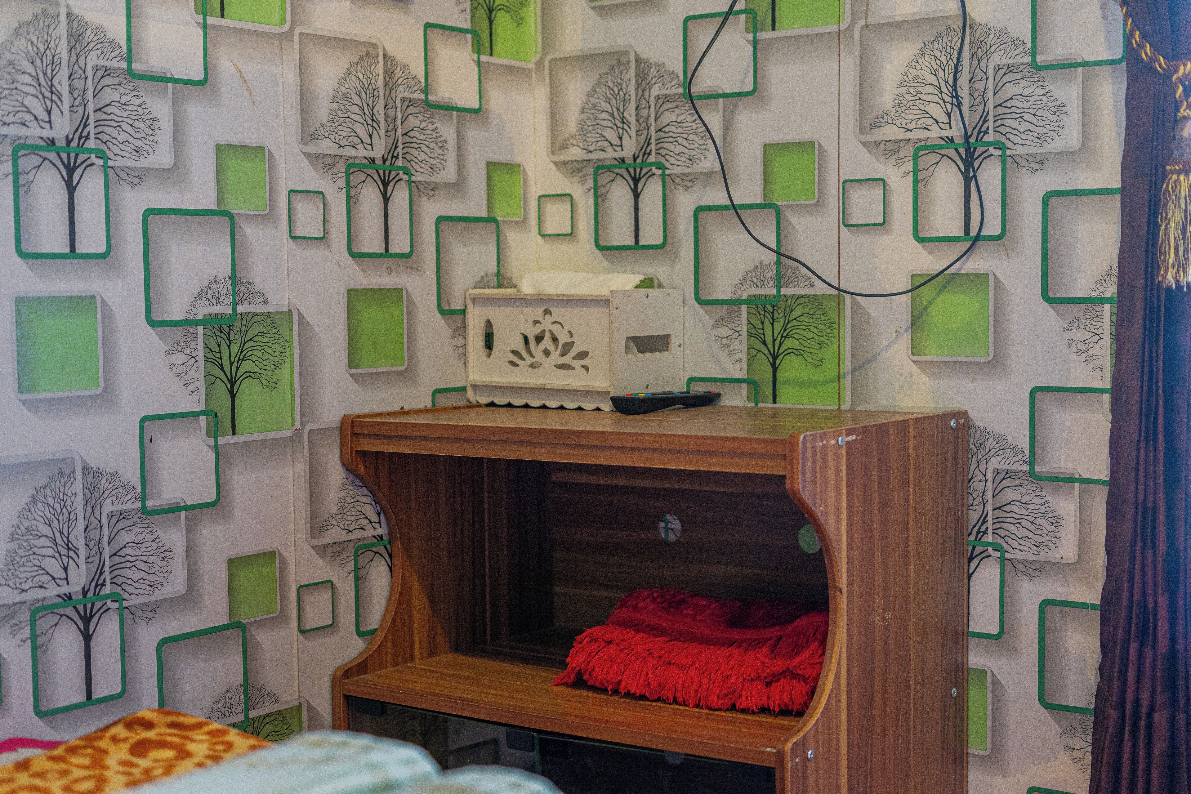 A child's play area with a wooden shelf and a red blanket.