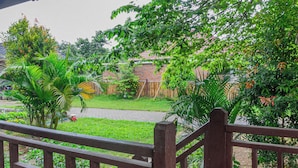 A wooden deck with a brick wall and lush greenery in the background.