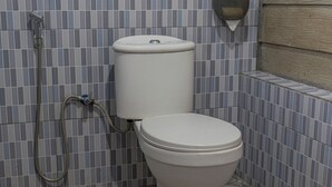 A bathroom with a toilet, a shower, and a tiled floor.