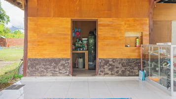 A wooden building with a tiled entrance and a blue patterned rug.