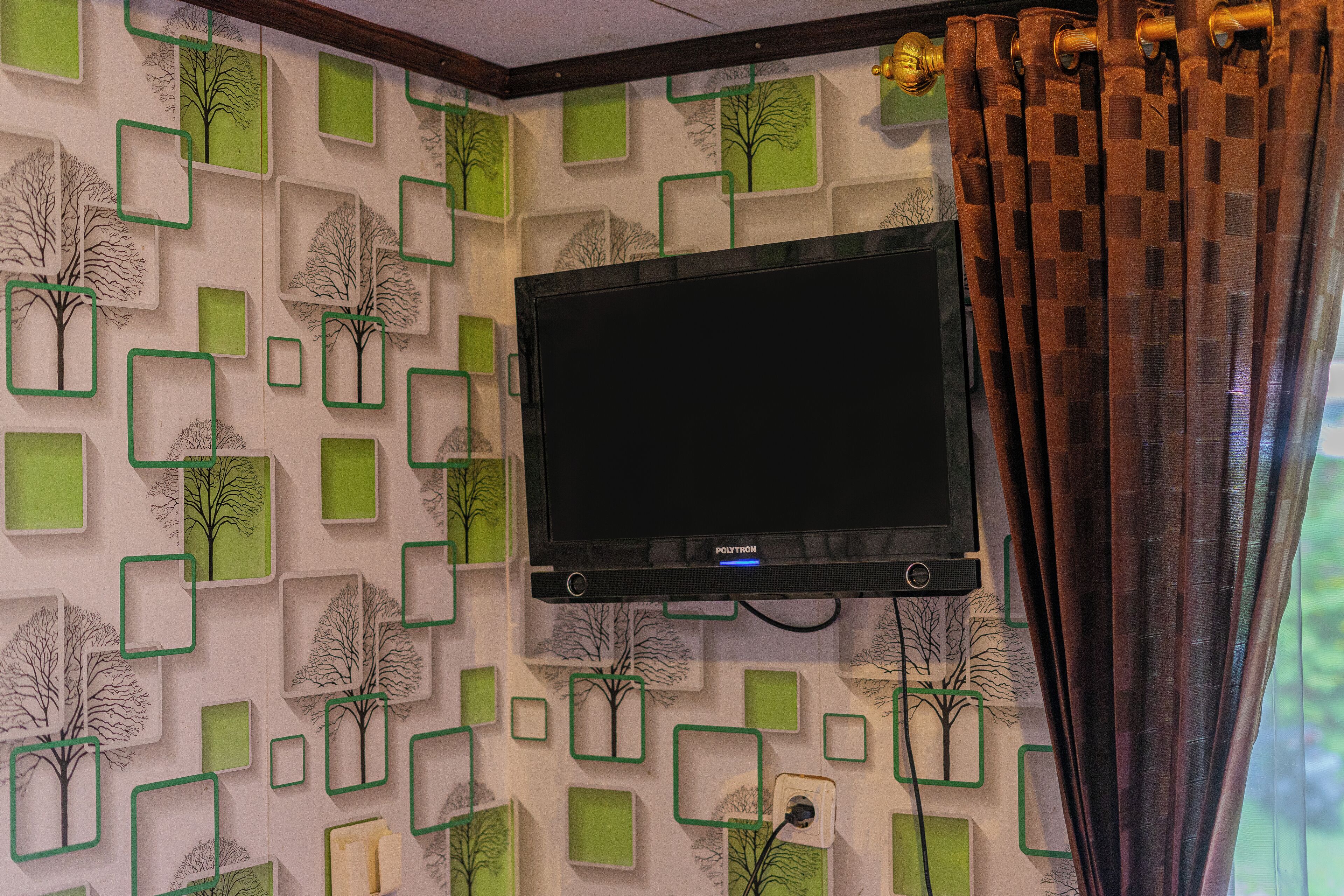 A television mounted on a wall with a geometric pattern of trees and squares.