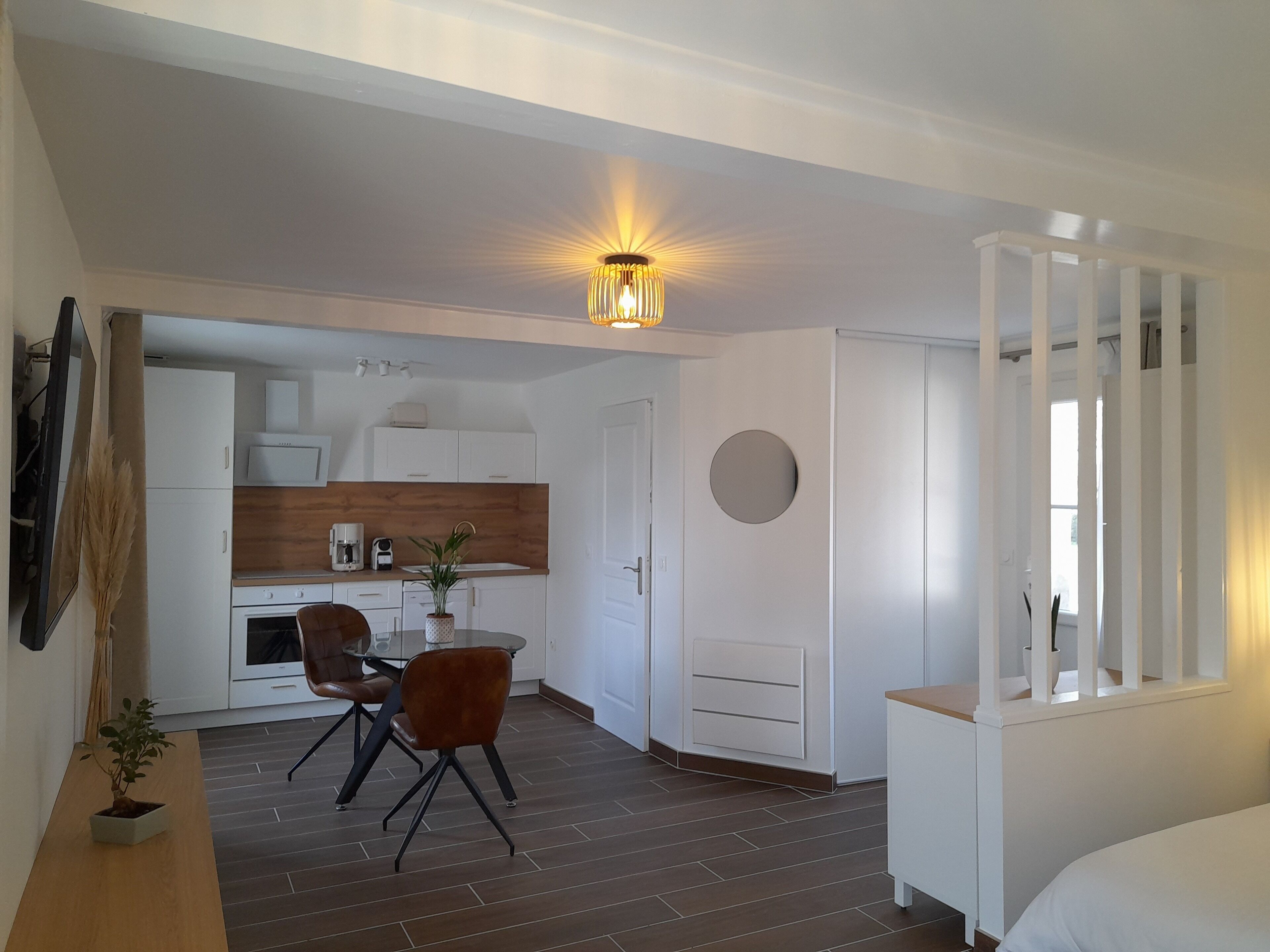 Een compacte, moderne kamer met een eethoek, kitchenette en een groot raam.