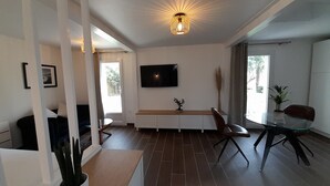 A modern living room with a flat-screen TV, a dining table, and a large window.