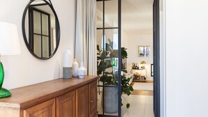 Una habitación con un armario de madera, un espejo, una planta en maceta y un ventanal corredero que da a otra habitación.