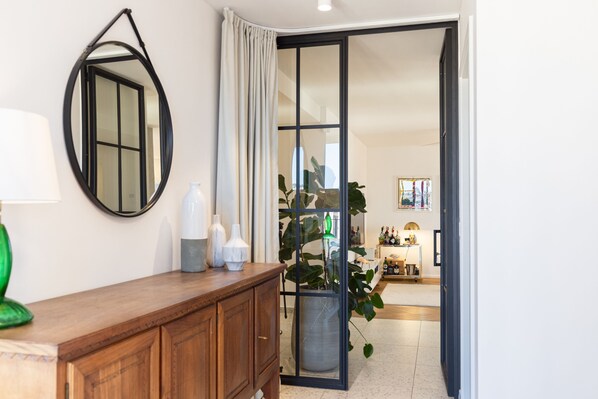 A room with a wooden cabinet, a mirror, a potted plant, and a sliding glass door leading to another room.