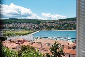 A coastal town with a marina, terracotta-roofed buildings, and a hilly backdrop.