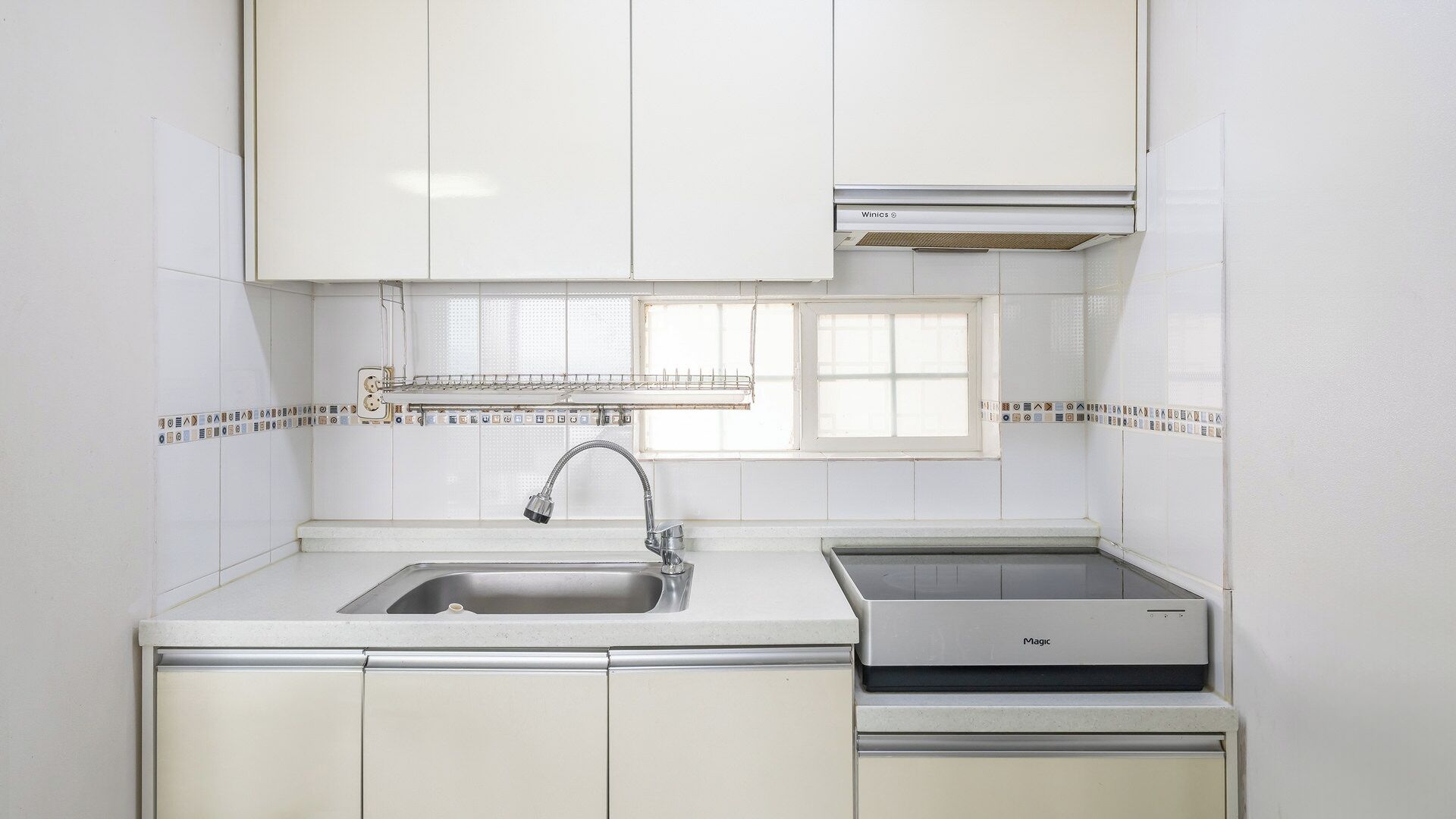 A kitchen with a sink, a stove, and a window above the sink.