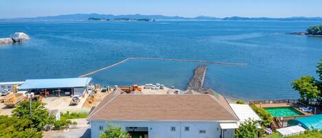 Una propiedad costera con piscina, muelle y vista despejada al mar.