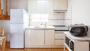 Una cucina moderna con mobili bianchi, forno integrato, microonde e macchina per il caffè sul piano di lavoro.