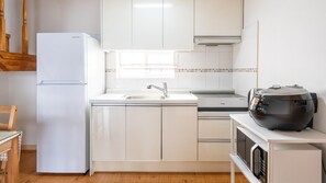 A modern kitchen with white cabinetry, a built-in oven, a microwave, and a coffee maker on the countertop.