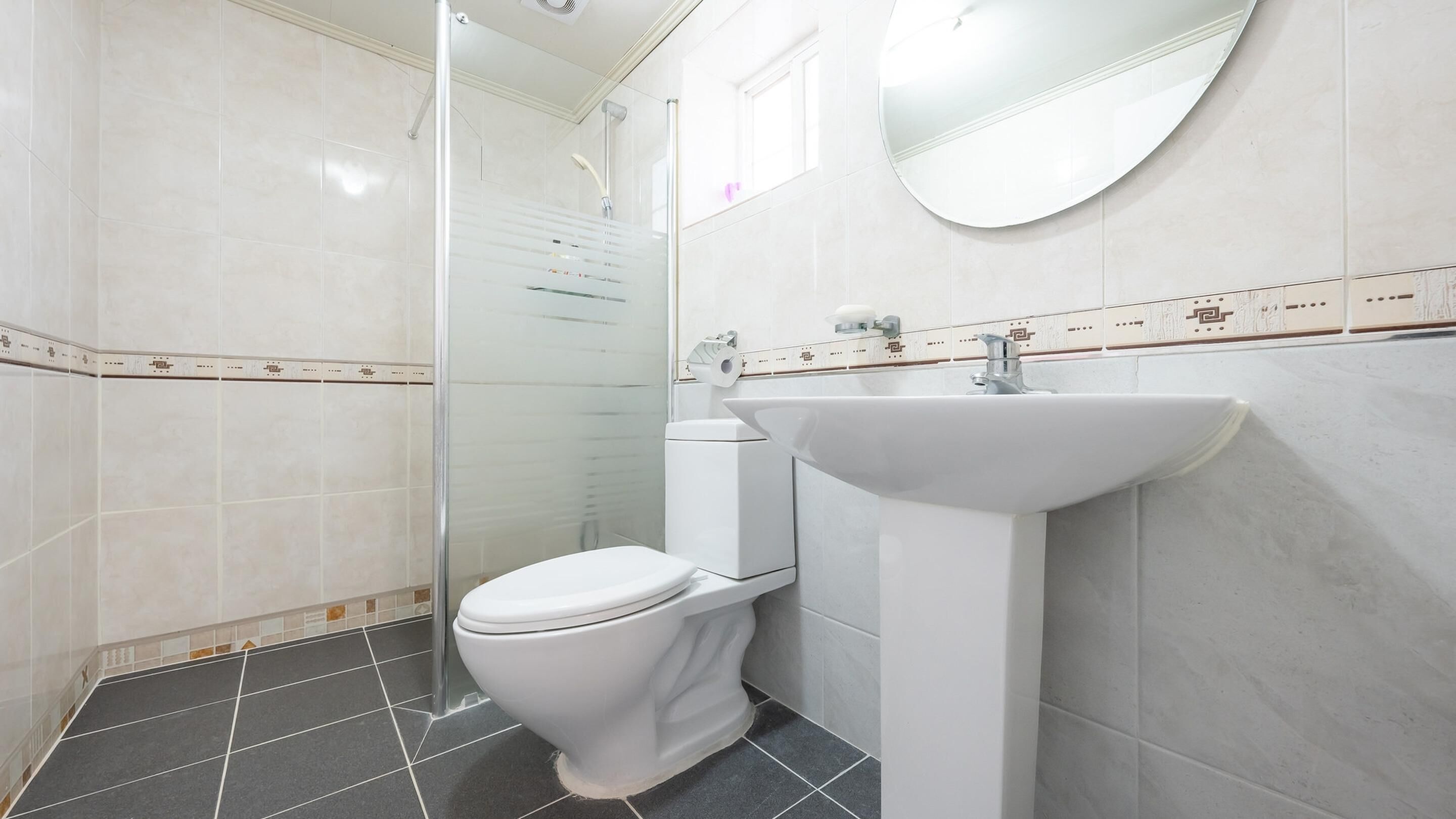 Et moderne badeværelse med toilet, vask og brusekabine i glas.