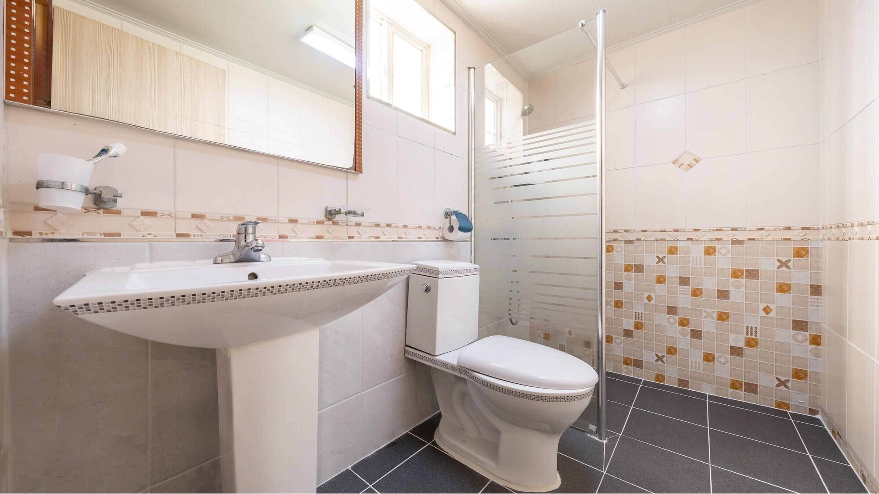 Un baño con lavamanos, inodoro y ducha blancos.