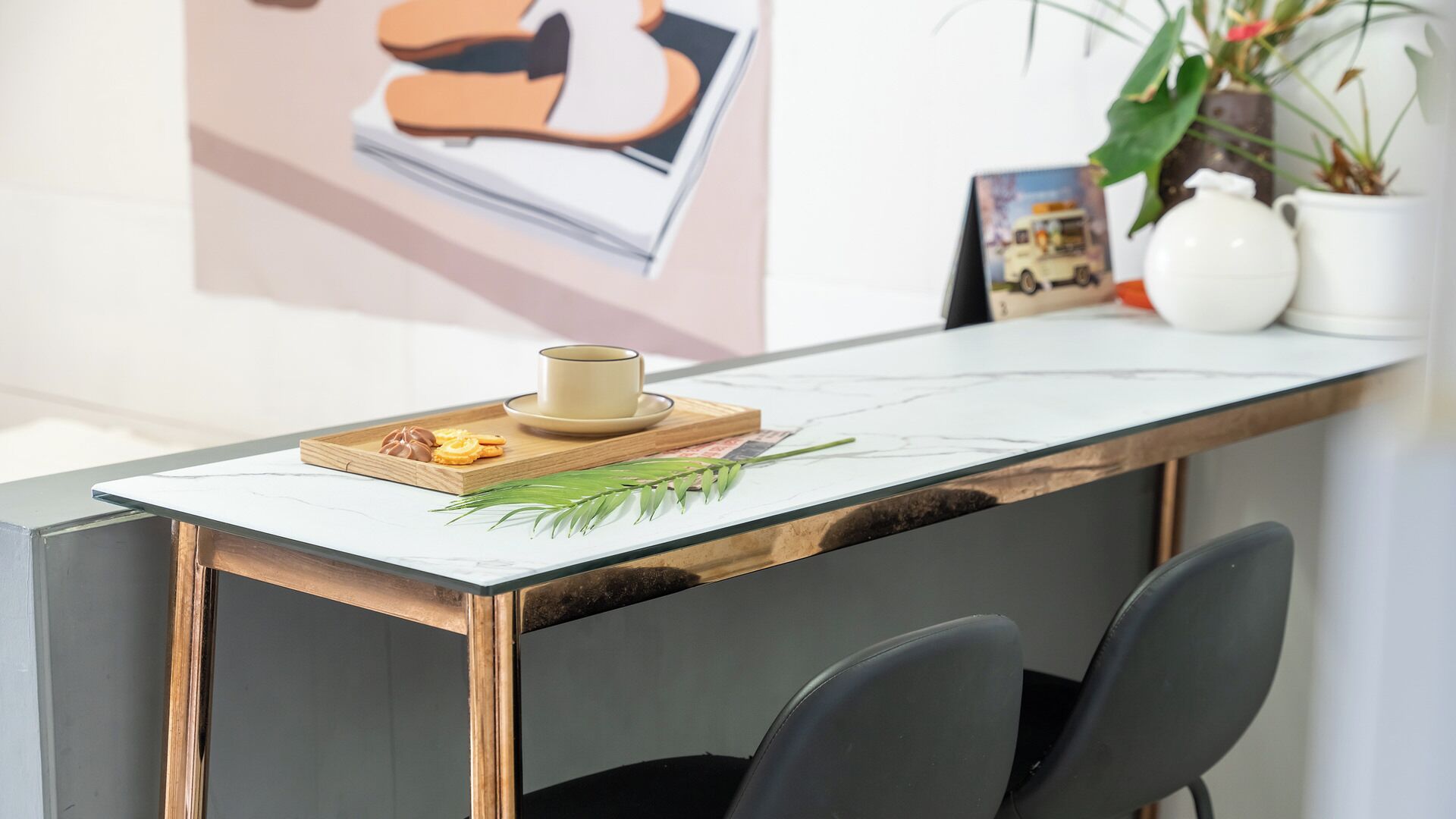 A reception desk with a marble top, a wooden tray with snacks, a cup, and a framed picture on the wall.