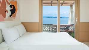 Una camera da letto con un letto grande, vista sul mare e un patio con tavolo e sedie.