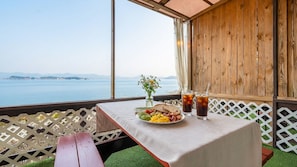 A table with food and drinks, a view of the sea, and a wooden wall. - Taean Tteulapbada Pension (Taean)