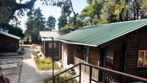 A row of wooden cabins with green roofs, a paved walkway, and a staircase leading to the cabins. - Tip N Top (Lansdowne)