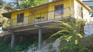 A yellow building with a balcony, concrete pillars, and greenery around. - Tip N Top (Lansdowne)