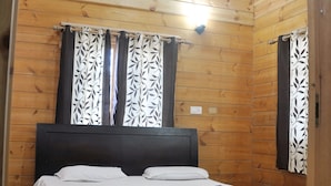 A wooden-paneled bedroom with a bed, two windows with patterned curtains, and a ceiling fan. - Tip N Top (Lansdowne)