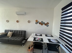 Relax in this stylish living space with a sofa, dining table for four, and decorative plates on the wall.