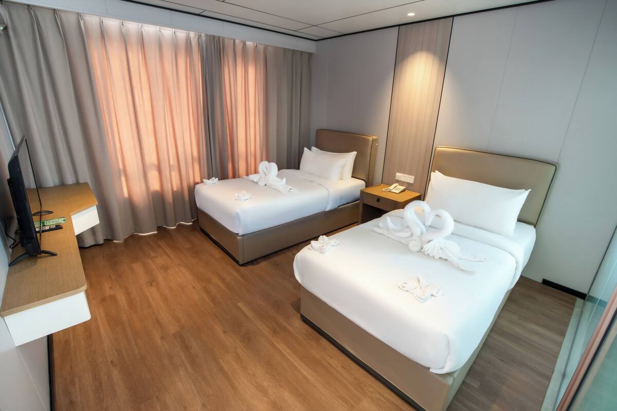 Een hotelkamer met twee bedden, een bureau en een televisie.