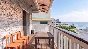 Een balkon met een stenen muur, een tafel en oranje stoelen.