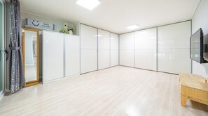 Una habitación amplia con piso de madera, un banco y un televisor en la pared.
