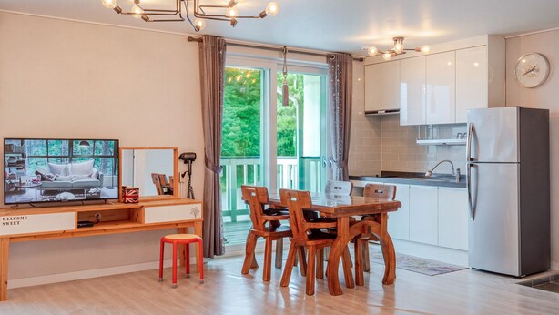 Een moderne keuken met een eethoek, een televisie en uitzicht op groen.
