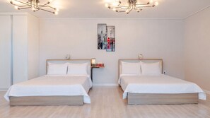 Une chambre d’hôtel avec deux lits, une table de chevet, une œuvre d’art accrochée au mur et un lustre moderne.