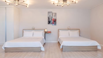 A hotel room with two beds, a nightstand, a wall-mounted artwork, and a modern chandelier.