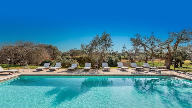 A clear blue pool with white lounge chairs and a tree-lined background. - Trulli e Pajare, Trullo Don Andrea a Carovigno (Carovigno)
