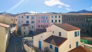 Une rue étroite, bordée de bâtiments des deux côtés, dont certains présentent des fenêtres et des portes apparentes.