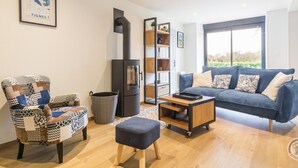 A modern living room with a patterned armchair, a blue sofa, a wooden coffee table, and a fireplace.